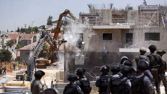 Backhoes demolishing buildings in combat zone